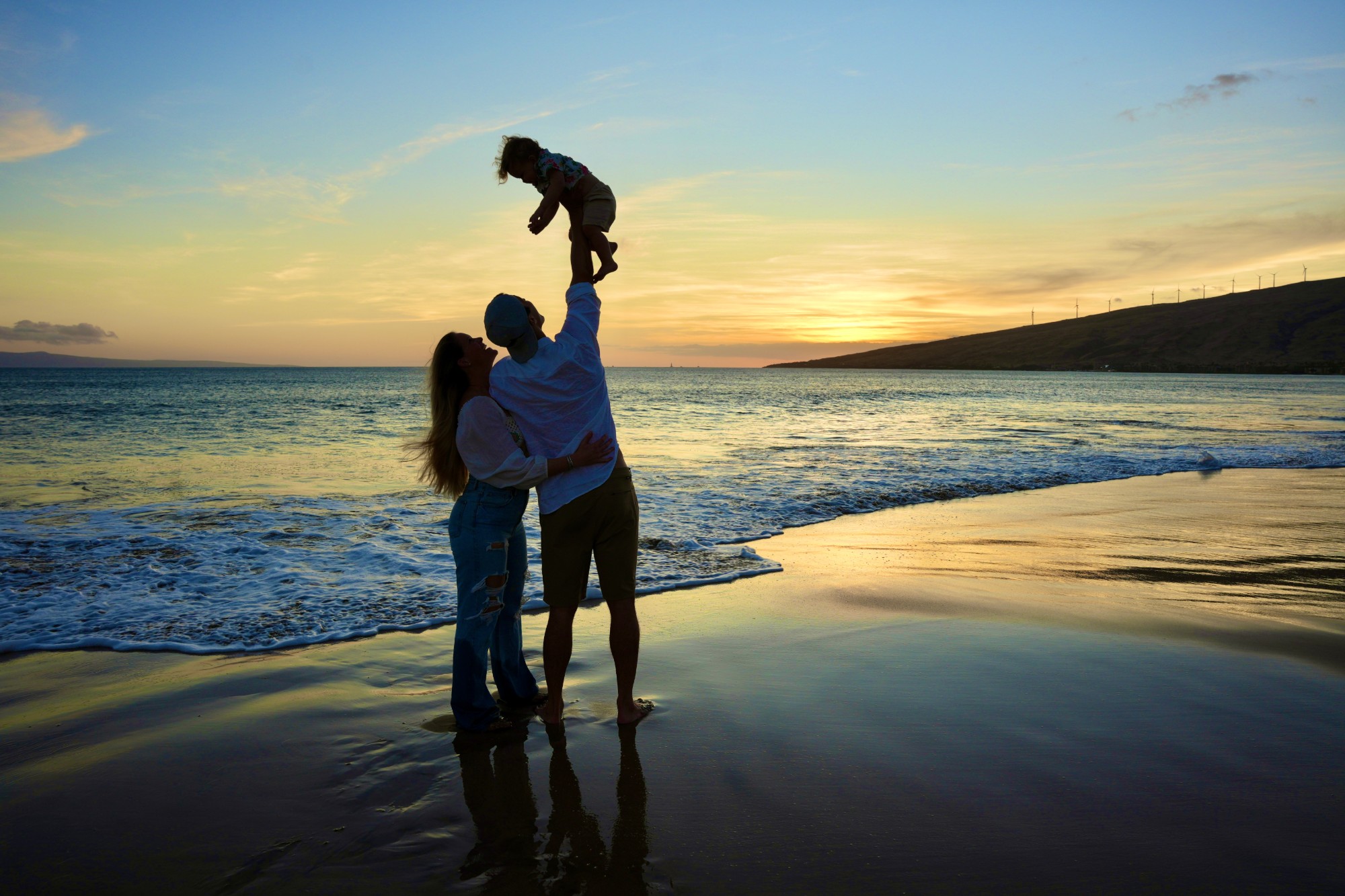 Family lifting their child at sunset on a Kīhei beach, South Maui