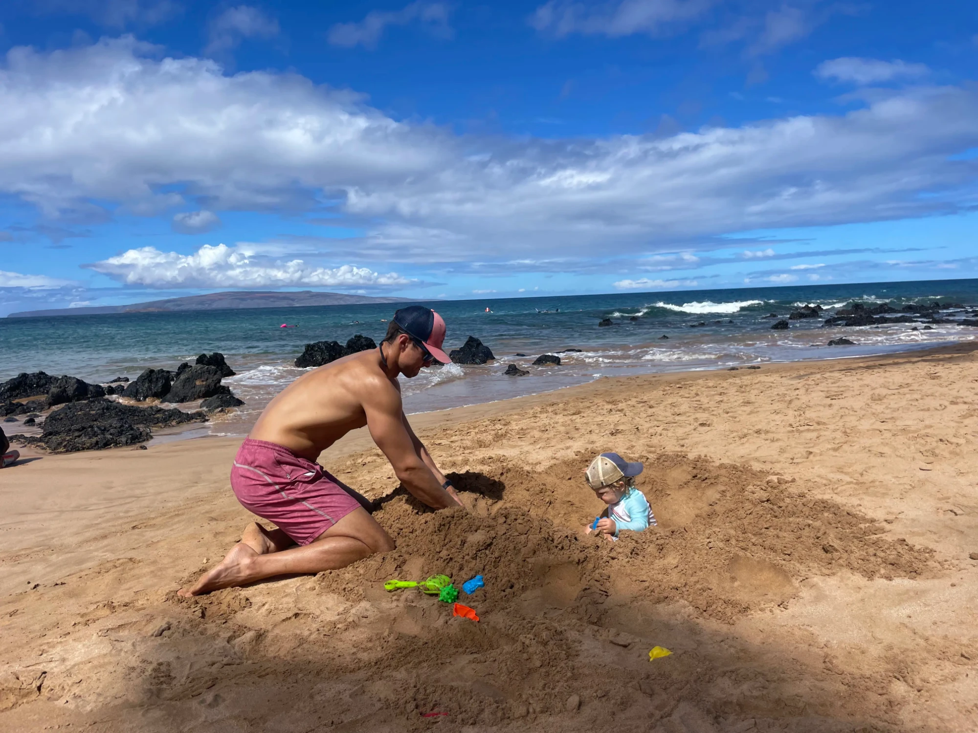 Father and child playing in the sand on a Wailea beach, South Maui